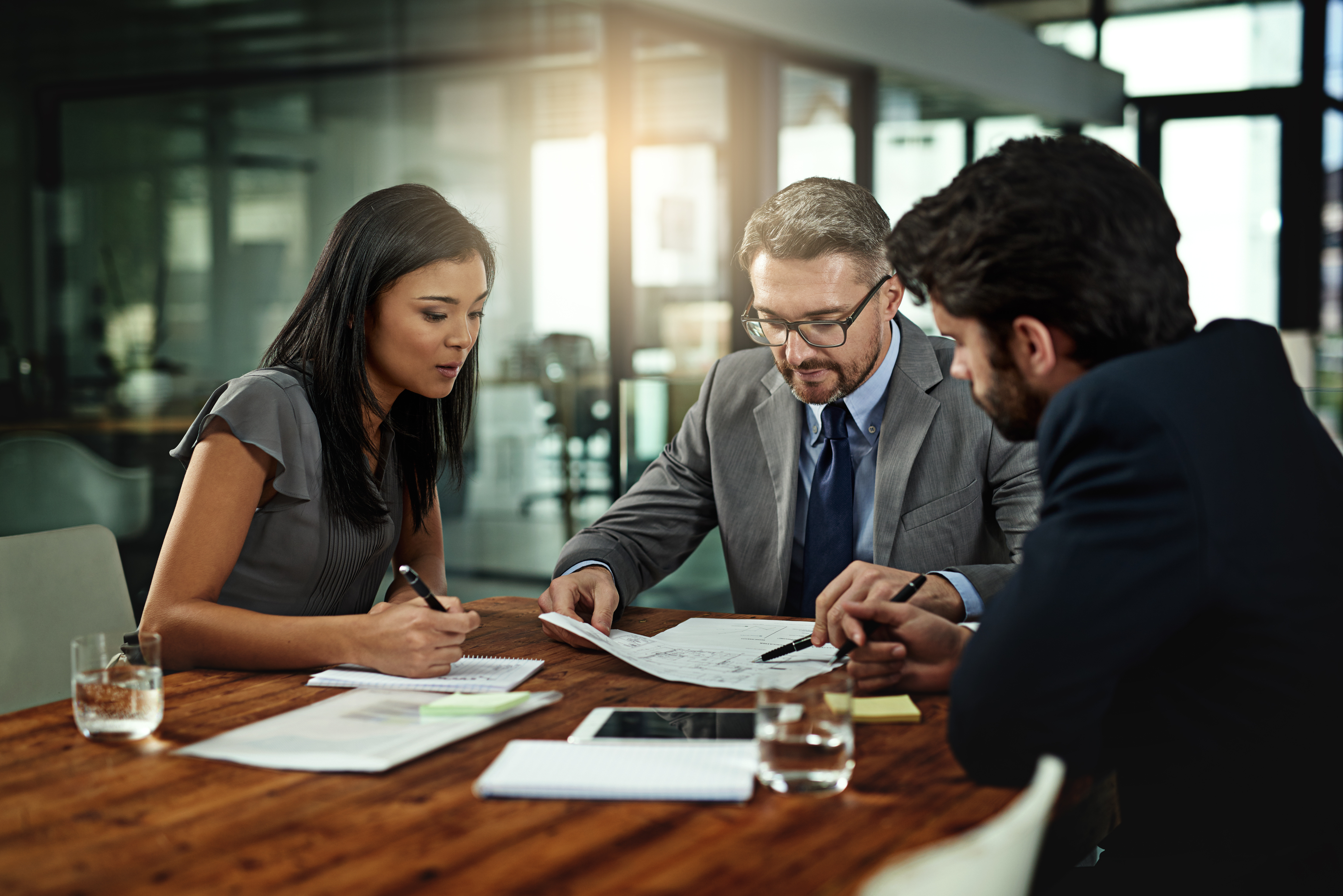 A group of workers in the legal sector sit around a board room table discussing work
